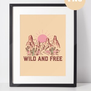 Puede incluir: Una impresi&oacute;n enmarcada con una ilustraci&oacute;n de paisaje des&eacute;rtico. La impresi&oacute;n presenta un sol rosa, monta&ntilde;as, cactus y un camino sinuoso. El texto "WILD AND FREE" est&aacute; impreso debajo de la imagen.
