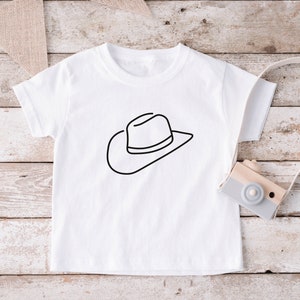 May include: White t-shirt with a black line drawing of a cowboy hat.