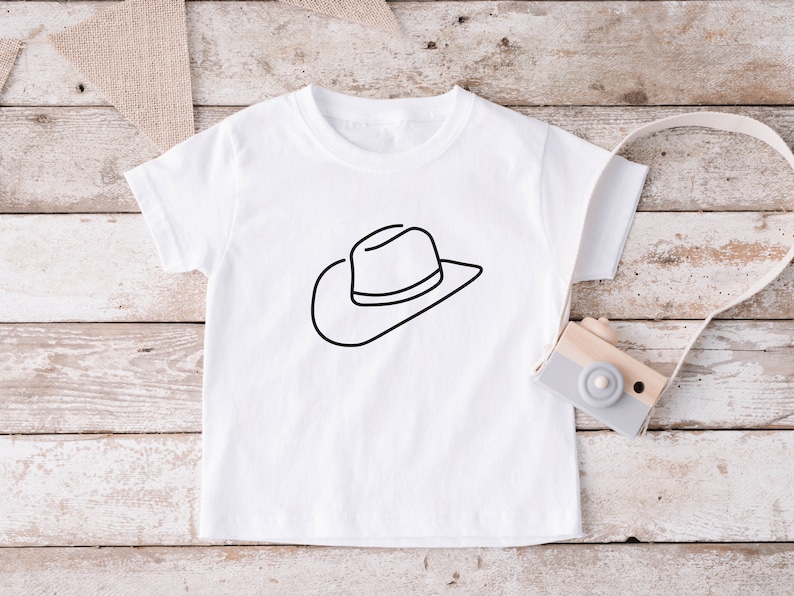 May include: White t-shirt with a black line drawing of a cowboy hat.