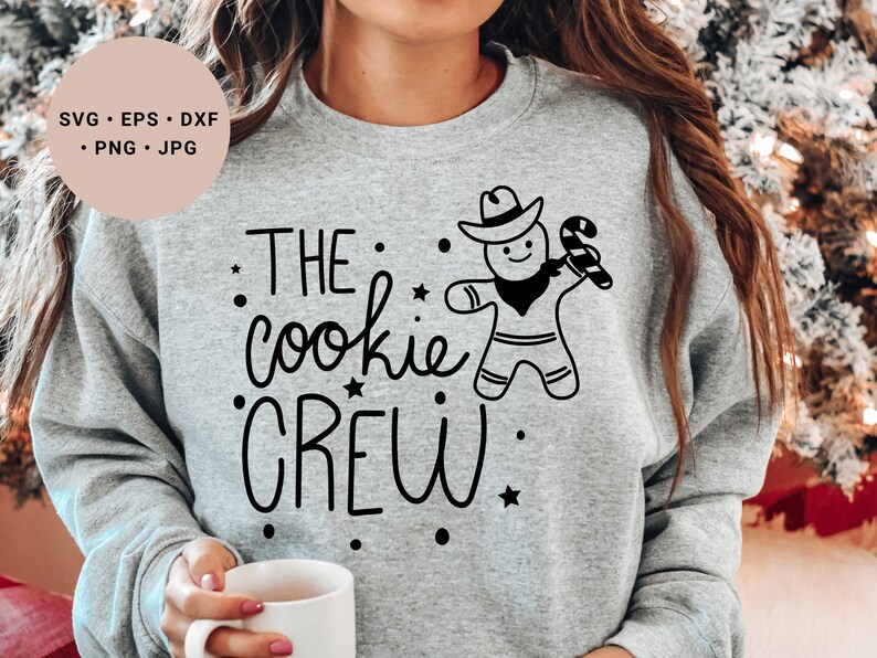 May include: A gray sweatshirt with the text "THE cookie CREW" and a gingerbread man wearing a cowboy hat and holding a candy cane.