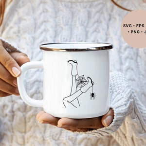 May include: White enamel mug with a black line drawing of a person's legs tangled in a spider web with a spider hanging from the web. The mug has a silver rim.
