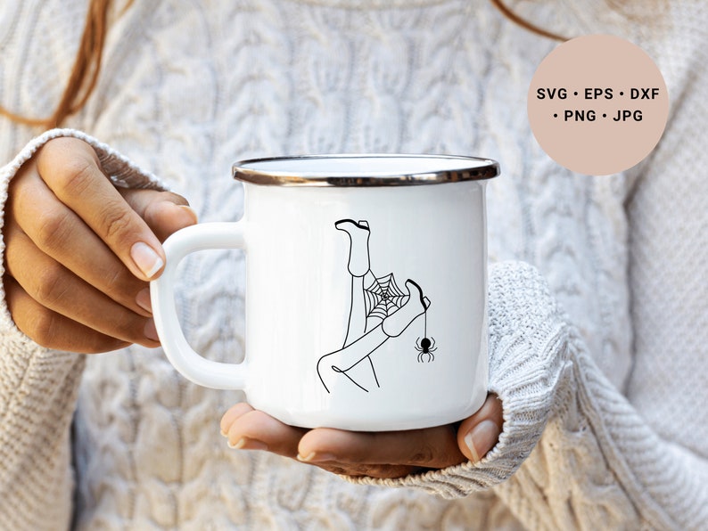 May include: White enamel mug with a black line drawing of a person's legs tangled in a spider web with a spider hanging from the web. The mug has a silver rim.
