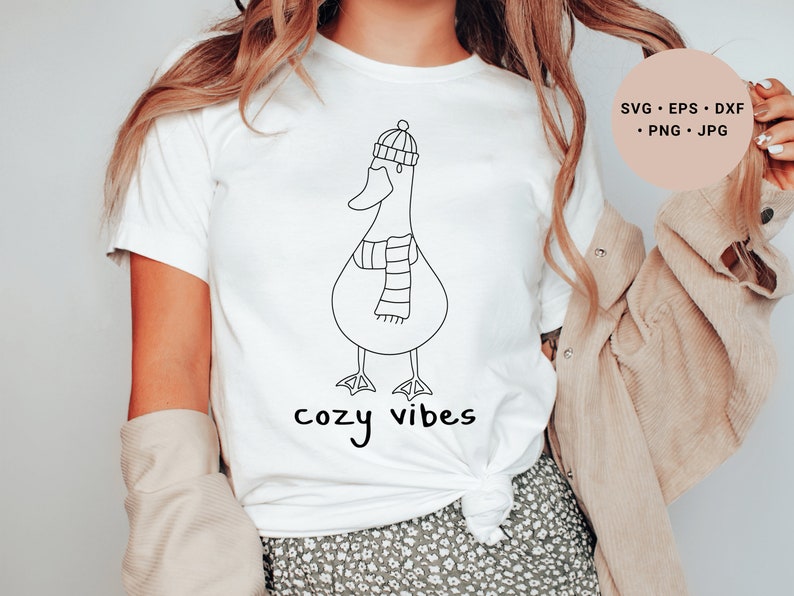 K&ouml;nnte beinhalten: Wei&szlig;es T-Shirt mit einer schwarzen Strichzeichnung eines Entchens mit Hut und Schal. Der Text "cozy vibes" ist unter dem Entchen gedruckt.