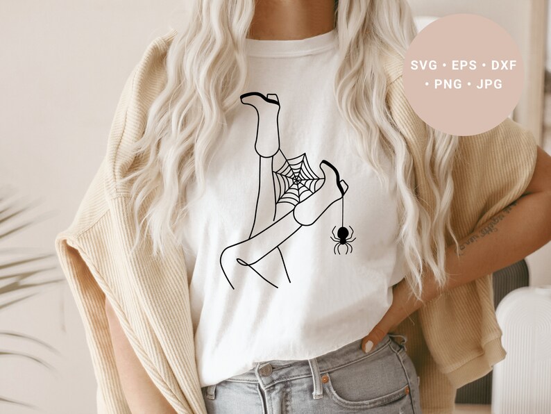 May include: A white t-shirt with a black line drawing of a person's legs tangled in a spider web with a spider hanging from the web.