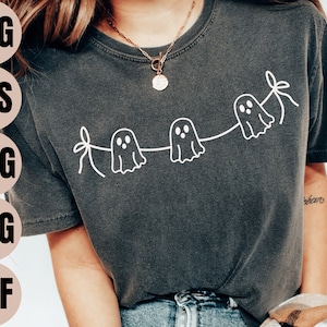 Könnte beinhalten: Ein dunkelgraues T-Shirt mit einer weißen Umrandung einer Geistergirlande. Die Girlande hat drei Geister mit Augen und eine Schleife am Ende.
