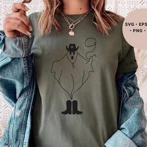 May include: A green t-shirt with a black line drawing of a ghost wearing a cowboy hat and boots. The ghost is holding a lasso. The text "SVG - EPS - DXF - PNG - JPG" is in the upper right corner of the image.