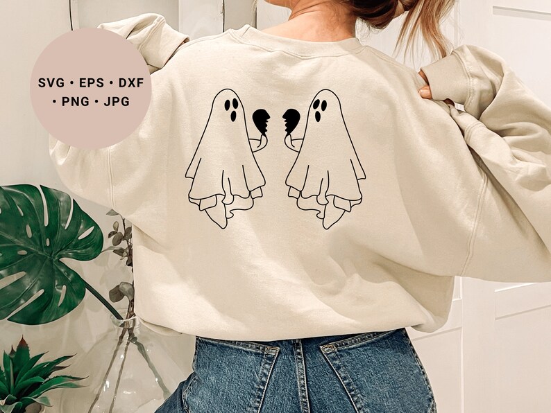 May include: A cream-coloured sweatshirt with a black outline of two ghosts holding broken hearts on the back. The text "SVG - EPS - DXF - PNG - JPG" is on a pink circle in the top left corner of the image.