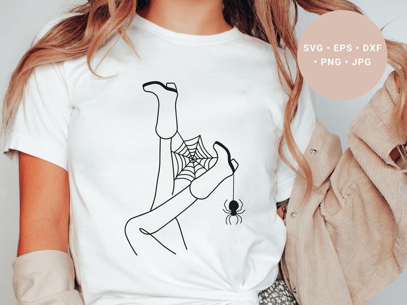 May include: A white t-shirt with a black line drawing of a person's legs tangled in a spider web with a spider hanging from the web.