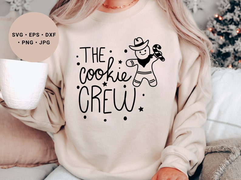 May include: A beige sweatshirt with the text "THE cookie CREW" in black lettering. A gingerbread man with a cowboy hat and candy cane is holding a star.