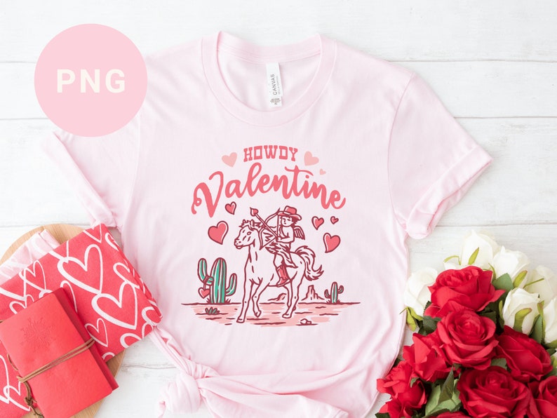 May include: Pink t-shirt with a cowboy riding a horse and the text "Howdy Valentine" in pink lettering with hearts.