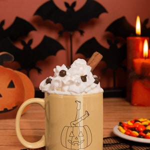 May include: A beige ceramic mug with a black and white illustration of a pumpkin with legs sticking out of the top. The mug has the text "Howdy Pumpkin" on the bottom. The mug is filled with whipped cream and chocolate chips and topped with a cinnamon stick. The mug is sitting on a black and white lace doily.