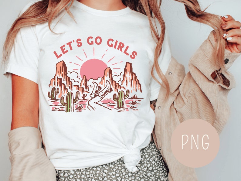 May include: White t-shirt with a graphic of a desert landscape with a pink sun, cacti, and the text "Let's Go Girls".
