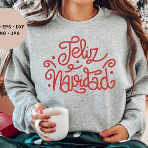 May include: A gray sweatshirt with the text "Feliz Navidad" in red cursive lettering.