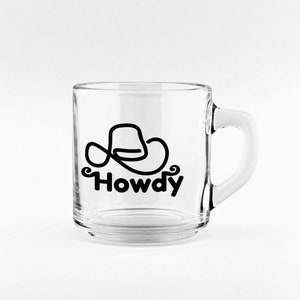 Może przedstawiać: Przezroczysty kubek szklany z czarnym kowbojskim kapeluszem i nadrukiem słowa "Howdy".