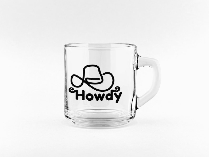 Może przedstawiać: Przezroczysty kubek szklany z czarnym kowbojskim kapeluszem i nadrukiem słowa "Howdy".