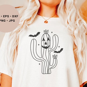 May include: A white t-shirt featuring a black line drawing of a cactus with a jack-o'-lantern face and bats flying around it. The text "SVG - EPS - DXF - PNG - JPG" is in the top left corner of the image.