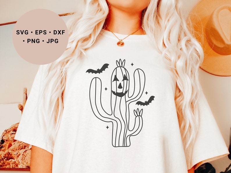 May include: A white t-shirt featuring a black line drawing of a cactus with a jack-o'-lantern face and bats flying around it. The text "SVG - EPS - DXF - PNG - JPG" is in the top left corner of the image.