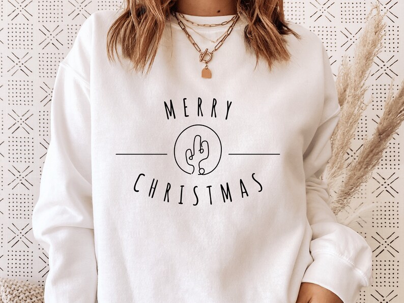 May include: White sweatshirt with a black graphic design that says "Merry Christmas" with a cactus illustration inside a circle.