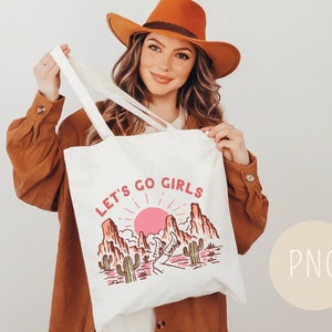 May include: White tote bag with a pink sunset and mountain landscape design. The text "Let's Go Girls" is printed in pink and white on the bag.