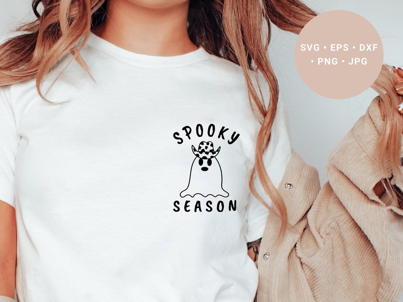 May include: A white t-shirt with a black and white illustration of a ghost wearing a cowboy hat. The text "Spooky Season" is written above the ghost.