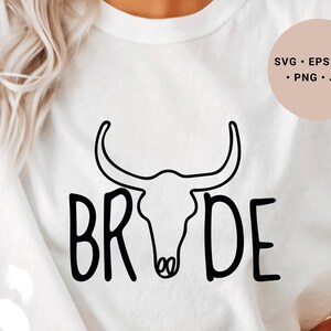 May include: White t-shirt with a black outline of a bull skull and the word "BRIDE" written in a stylized font.