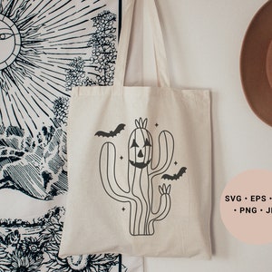 May include: A white tote bag featuring a black line drawing of a cactus with a jack-o'-lantern face and bats flying around it. The text "SVG - EPS - DXF - PNG - JPG" is printed on a pink circle in the bottom right corner of the image.
