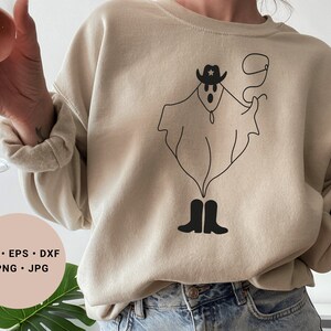May include: A beige sweatshirt with a black line drawing of a ghost wearing a cowboy hat and boots. The ghost is holding a lasso. The text "SVG - EPS - DXF - PNG - JPG" is on a pink circle in the lower left corner of the image.