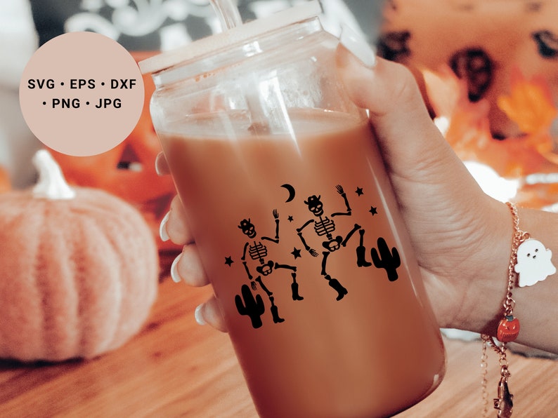 May include: A clear glass tumbler with a brown beverage inside. The tumbler has a black design of two skeletons dancing with a cactus and stars. The text "SVG. EPS. DXF. PNG. JPG" is visible in the background.
