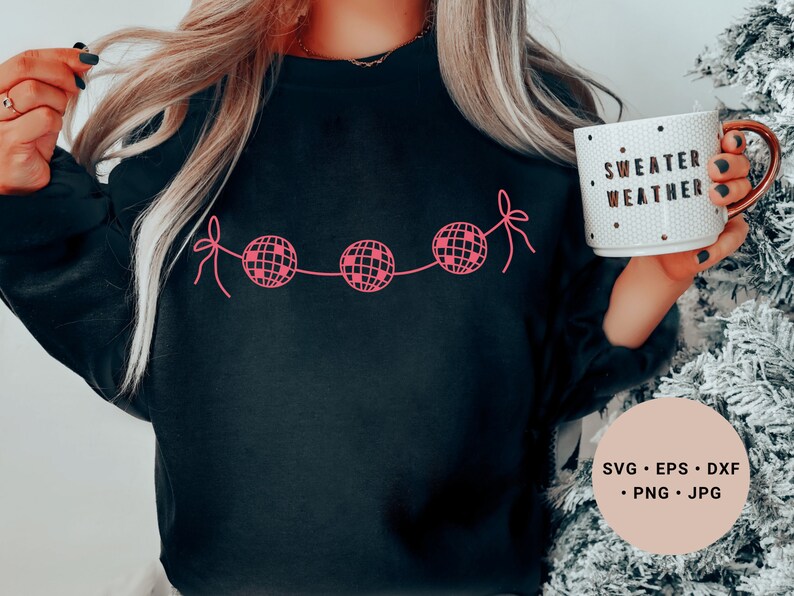 May include: A black sweatshirt with a pink design of a string of disco balls with the text "Sweater Weather" on a white mug.