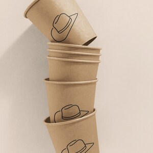 May include: A stack of six brown paper cups with a black line drawing of a cowboy hat on each cup.