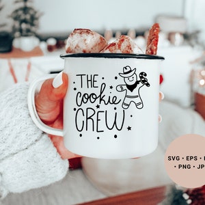 May include: White enamel mug with a black design of a gingerbread man wearing a cowboy hat and holding a candy cane. The text on the mug reads "The cookie crew".