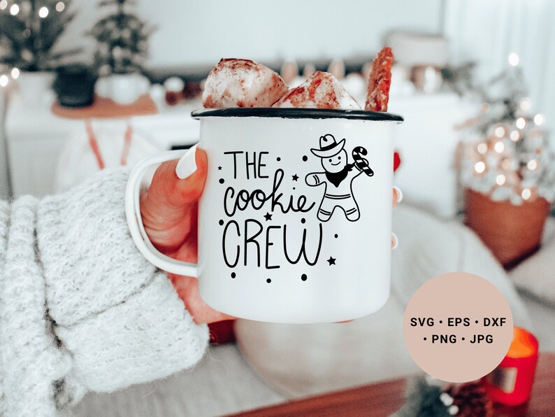 May include: White enamel mug with a black design of a gingerbread man wearing a cowboy hat and holding a candy cane. The text on the mug reads "The cookie crew".