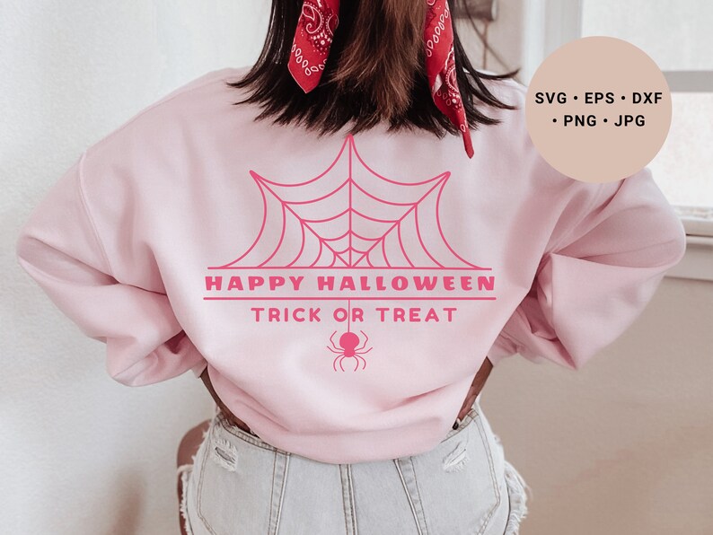 K&ouml;nnte beinhalten: Rosafarbener Pullover mit einem pinkfarbenen Spinnennetz-Motiv und dem Text "Happy Halloween Trick or Treat".