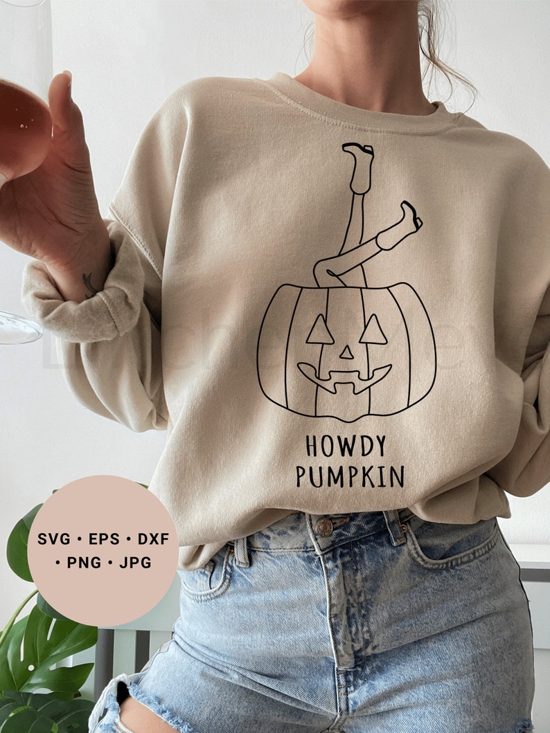 May include: A beige sweatshirt with a black line drawing of a person with their legs sticking out of a jack-o'-lantern. The text "Howdy Pumpkin" is printed below the image.