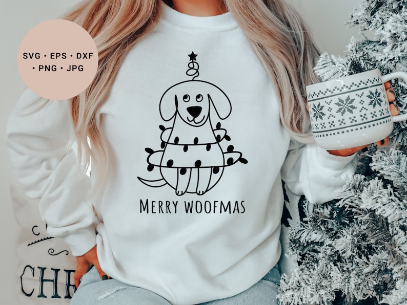 May include: White sweatshirt with a black line drawing of a dog dressed as a Christmas tree. The text "Merry Woofmas" is printed below the dog.