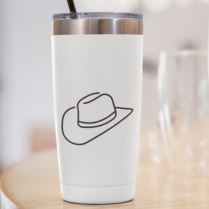 May include: White stainless steel tumbler with a black line drawing of a cowboy hat on the side. The tumbler has a black lid and a black straw.