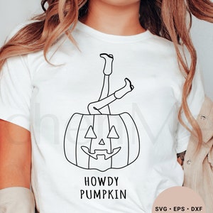 May include: White t-shirt with a black line drawing of a person's legs sticking out of a pumpkin with a face. The text "Howdy Pumpkin" is below the pumpkin. The text "SVG. EPS. DXF. PNG. JPG" is in the bottom right corner.