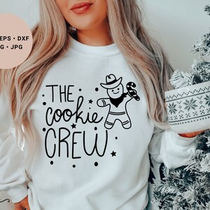 May include: White sweatshirt with black text that reads "THE cookie CREW" and a gingerbread man graphic.