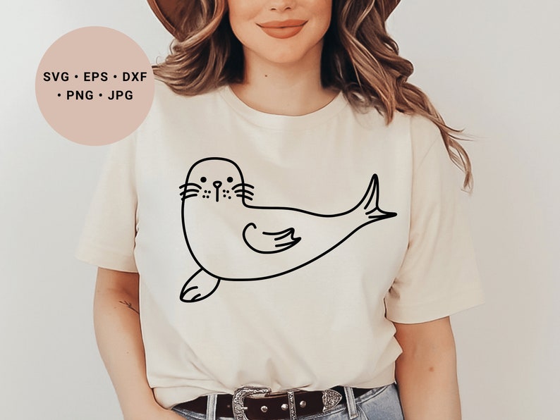 May include: A white t-shirt with a black line drawing of a seal on the front. The seal is facing left and has a simple, cartoon-like design.