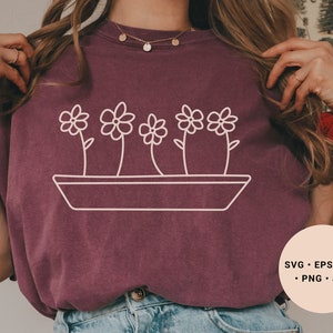 Könnte beinhalten: Ein maroonfarbenes T-Shirt mit einer weißen Umrandung einer Topfpflanze mit fünf Blüten. Der Text "SVG - EPS - DXF - PNG - JPG" befindet sich in der rechten unteren Ecke des Bildes.