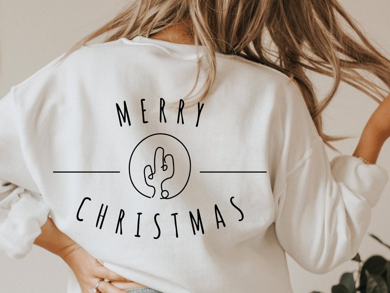 May include: White sweatshirt with the text "Merry Christmas" and a line drawing of a cactus in a circle.