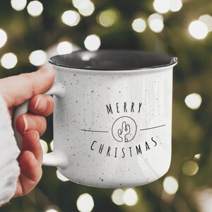 May include: White ceramic mug with black speckles and a black rim. The mug has a cactus graphic and the text "Merry Christmas".