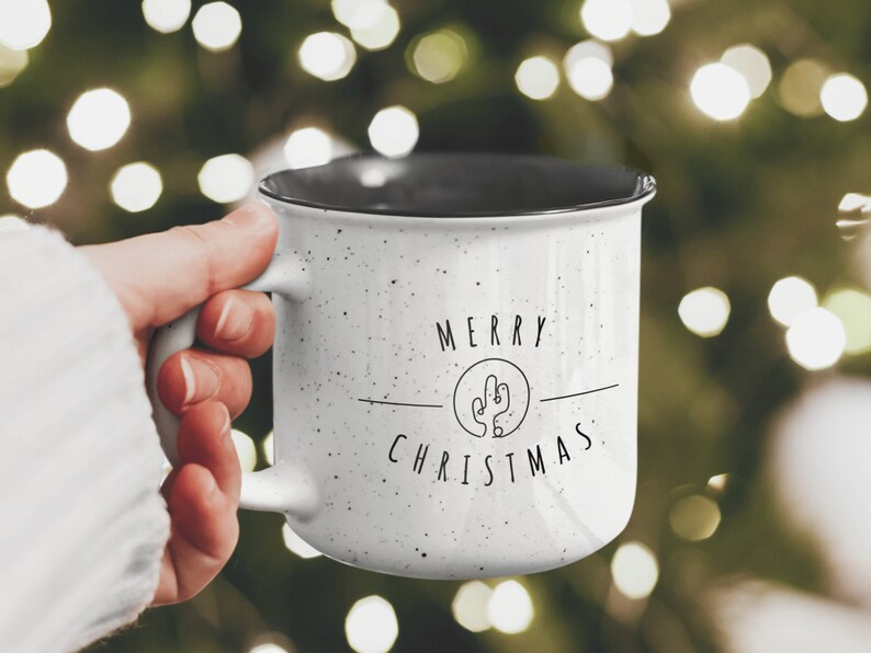 May include: White ceramic mug with black speckles and a black rim. The mug has a cactus graphic and the text "Merry Christmas".