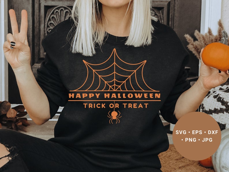 K&ouml;nnte beinhalten: Ein schwarzes Sweatshirt mit einem orangefarbenen Grafikdesign eines Spinnennetzes und dem Text "Happy Halloween Trick or Treat".