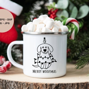 May include: White enamel mug with a black and white illustration of a dog wearing Christmas lights and the text "Merry Woofmas". The mug is filled with marshmallows and a candy cane is in the background.