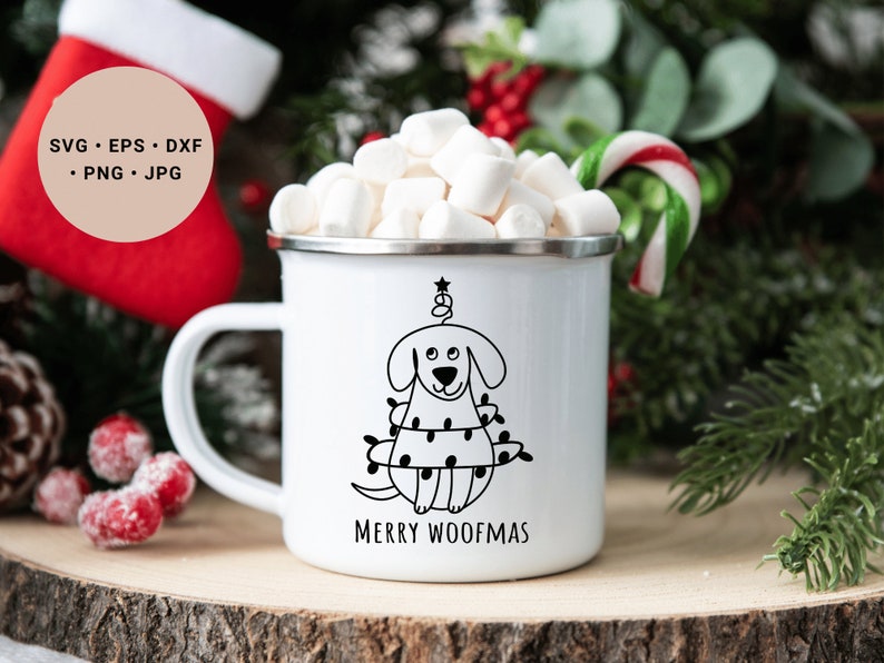 May include: White enamel mug with a black and white illustration of a dog wearing Christmas lights and the text "Merry Woofmas". The mug is filled with marshmallows and a candy cane is in the background.