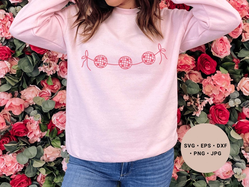 May include: A pink sweatshirt with a graphic of a string of disco balls with pink bows. The text "SVG - EPS - DXF - PNG - JPG" is in the lower right corner of the image.