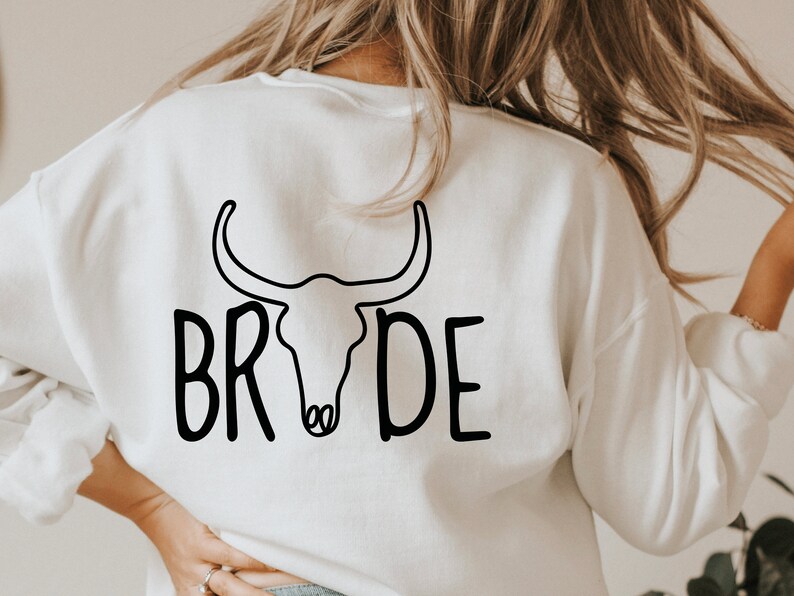 May include: White sweatshirt with a black bull skull graphic and the word "BRIDE" written in a stylized font.