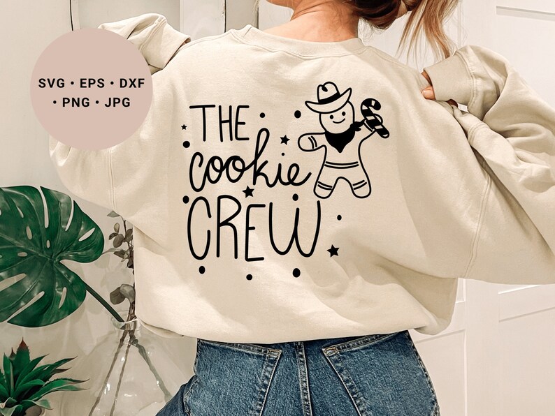 May include: A cream-colored sweatshirt with black text that reads "THE cookie CREW" and a black and white illustration of a gingerbread person wearing a cowboy hat and holding a candy cane.
