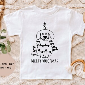 May include: White t-shirt with a black and white illustration of a dog wearing a Christmas tree costume. The text "Merry Woofmas" is printed below the illustration.